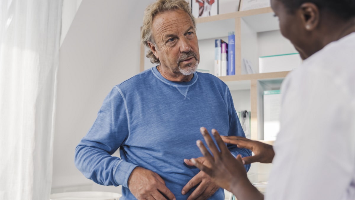 Oudere man in blauw shirt met stomaverpleegkundige