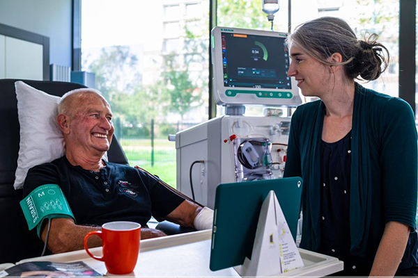 man ligt aan dialysemachine en praat met vrouw