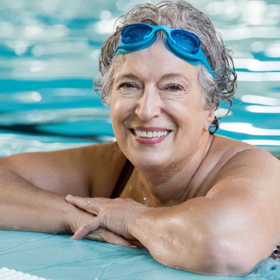 vrouw in zwembad met zwembril op haar voorhoofd