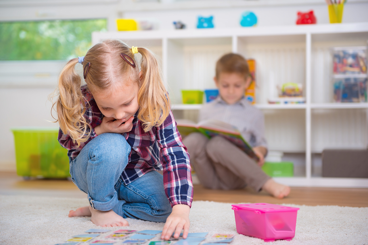 Cute little girl play board game, boy read book