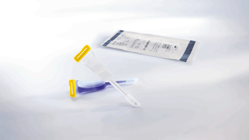 Twee tubes huidlijm met blauwe huidlijm op een grijze ondergrond. Op de achtergrond is de peel-offblisterverpakking van de huidlijm zichtbaar.