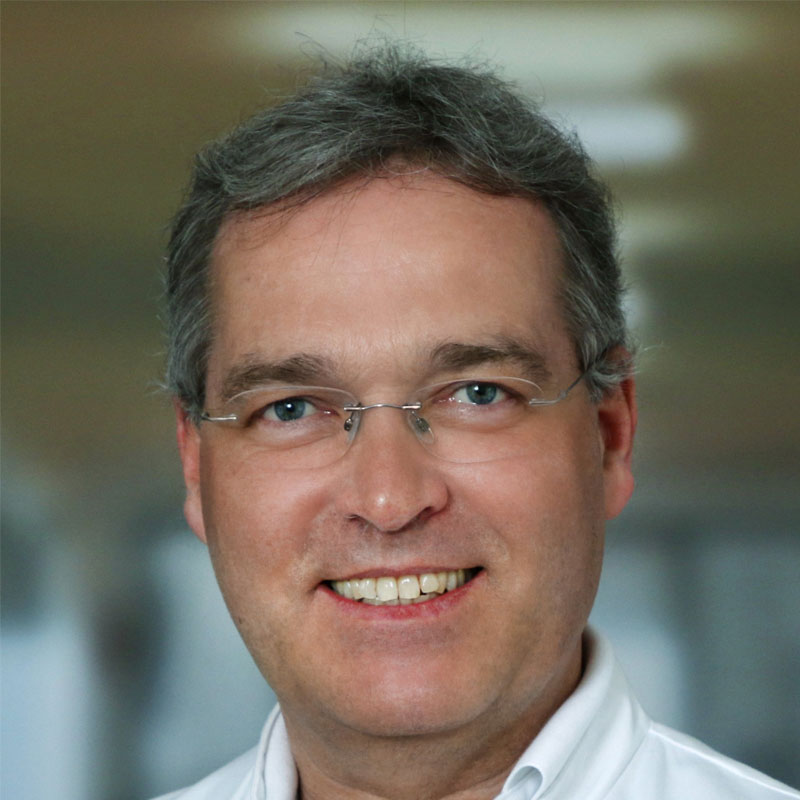 Portret van professor Markus Golling in een doktersjas die zelfverzekerd in de camera glimlacht