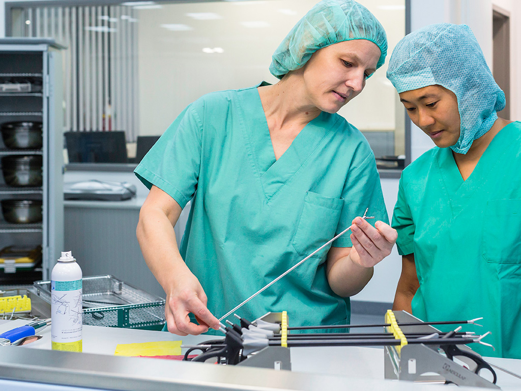 vrouw geeft mannelijke collega uitleg over onderhoud van laparoscopische instrumenten